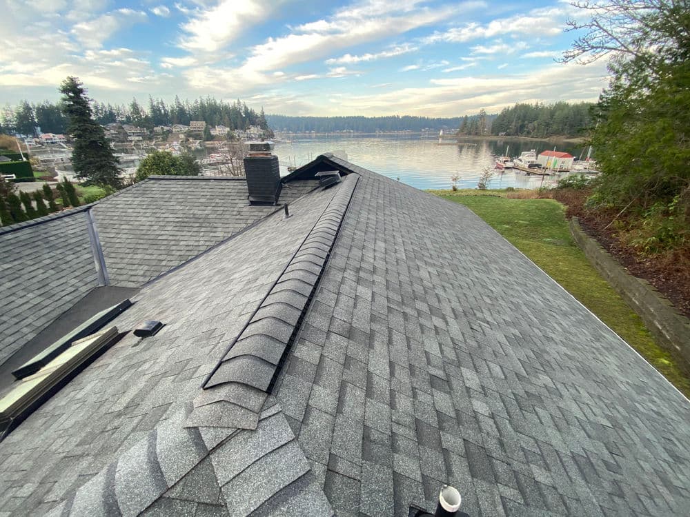 Roof shingles overlooking a scenic lake and boats, surrounded by trees and houses.